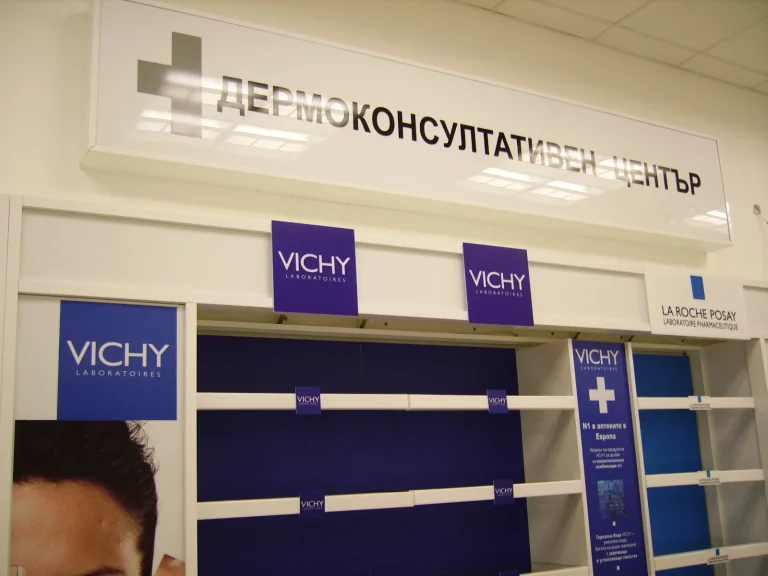 Светеща табела над стелажи с брандирани рекламни елементи на козметични марки в аптека.