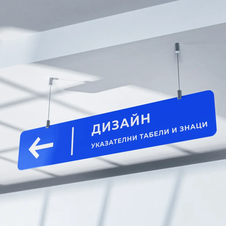 Висяща синя указателна табела със стрелка наляво и надпис Дизайн, монтирана към тавана чрез метални въжета.